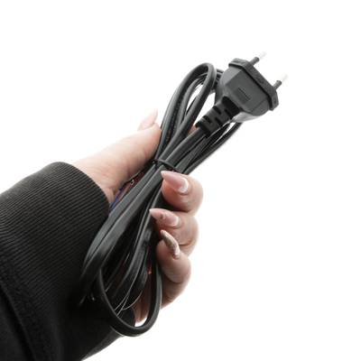 Detailní záběr ruky držící stočený černý elektrický vodič s dvoukolíkovou zástrčkou, izolovaný bílým pozadím pro řešení osvětlení LED.