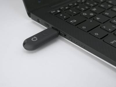 USB flash disk připojený k notebooku na bílém pozadí, který symbolizuje konektivitu a technologie v moderních řešeních LED osvětlení.