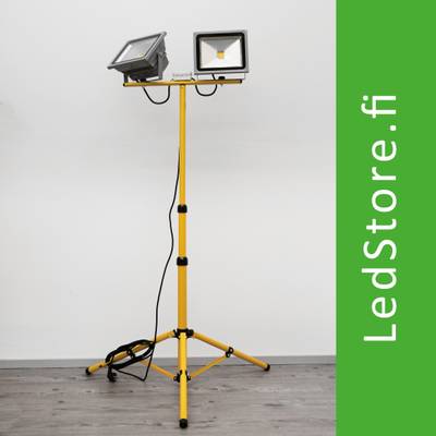 Dvouhlavé žluté pracovní světlo LED se stojanem, bílé pozadí. Vedle zelený text "LedStore.fi". Ideální pro profesionální a domácí osvětlení.