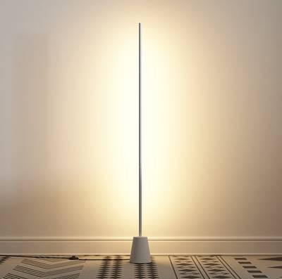 Minimalistická stojací lampa LED, štíhlá tyčová konstrukce, teplé náladové světlo osvětluje strukturovanou podlahu a stěny.