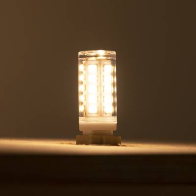 Teplá LED lampa zářící na tmavém pozadí, umístěná vertikálně pro optimální rozptyl světla a energetickou účinnost. Ideální pro ekologicky šetrné domácnosti.