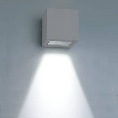 Nástěnné svítidlo LED ve tvaru kostky osvětluje jasným paprskem směrem dolů jemně modrou stěnu a zvýrazňuje moderní interiér energeticky úsporným osvětlením.