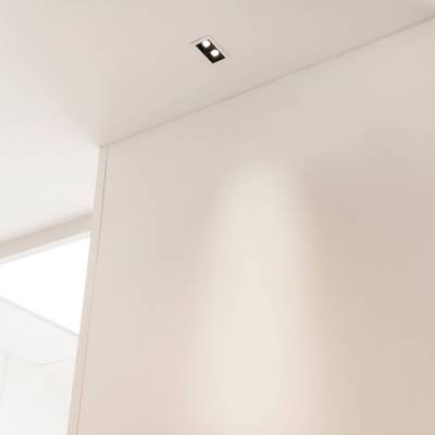 Minimalistická místnost s bílým stropem a stěnami a stylovým obdélníkovým vestavným svítidlem LED pro moderní osvětlení.