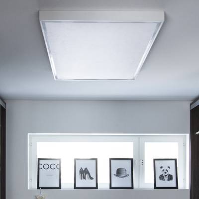 Stropní LED světlo osvětluje monochromatické zarámované obrázky textu, bot, klobouku a pandy na polici vedle okna v moderním domácím interiéru.