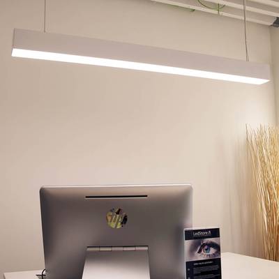 Stylová stolní LED lampa, která osvětluje moderní kancelář s počítačem na bílém stole; v pozadí dekorativní větve ve vysoké váze.