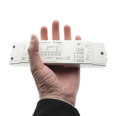 V ruce bílé obdélníkové zařízení zobrazující technické informace a symboly a slovo "Zigbee" spojené s technologií LED osvětlení.