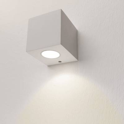 Alternativní text: Nástěnné LED svítidlo ve tvaru kostky osvětluje měkké bílé světlo na strukturované stěně, moderní design osvětlení pro váš domov nebo kancelář.