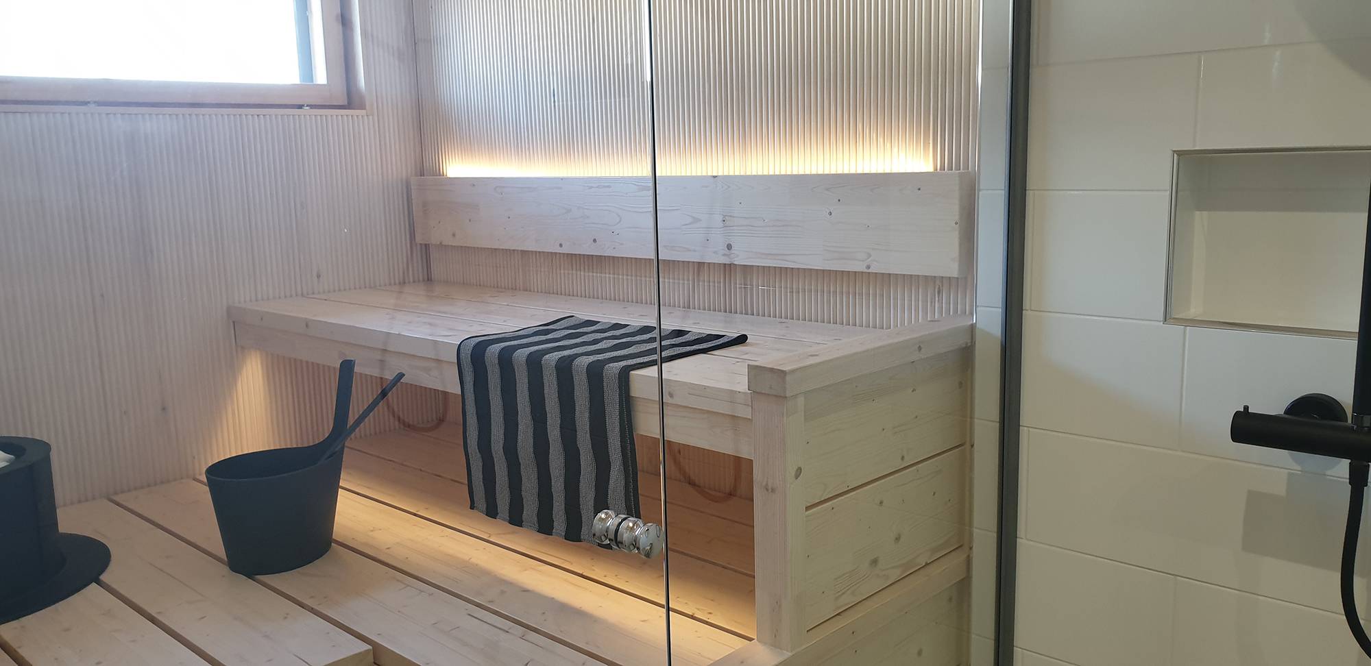 LED pásek na zadní straně opěradla sauny osvětluje atmosférické světlo směrem nahoru a dolů pod strop. Ledstore.fi