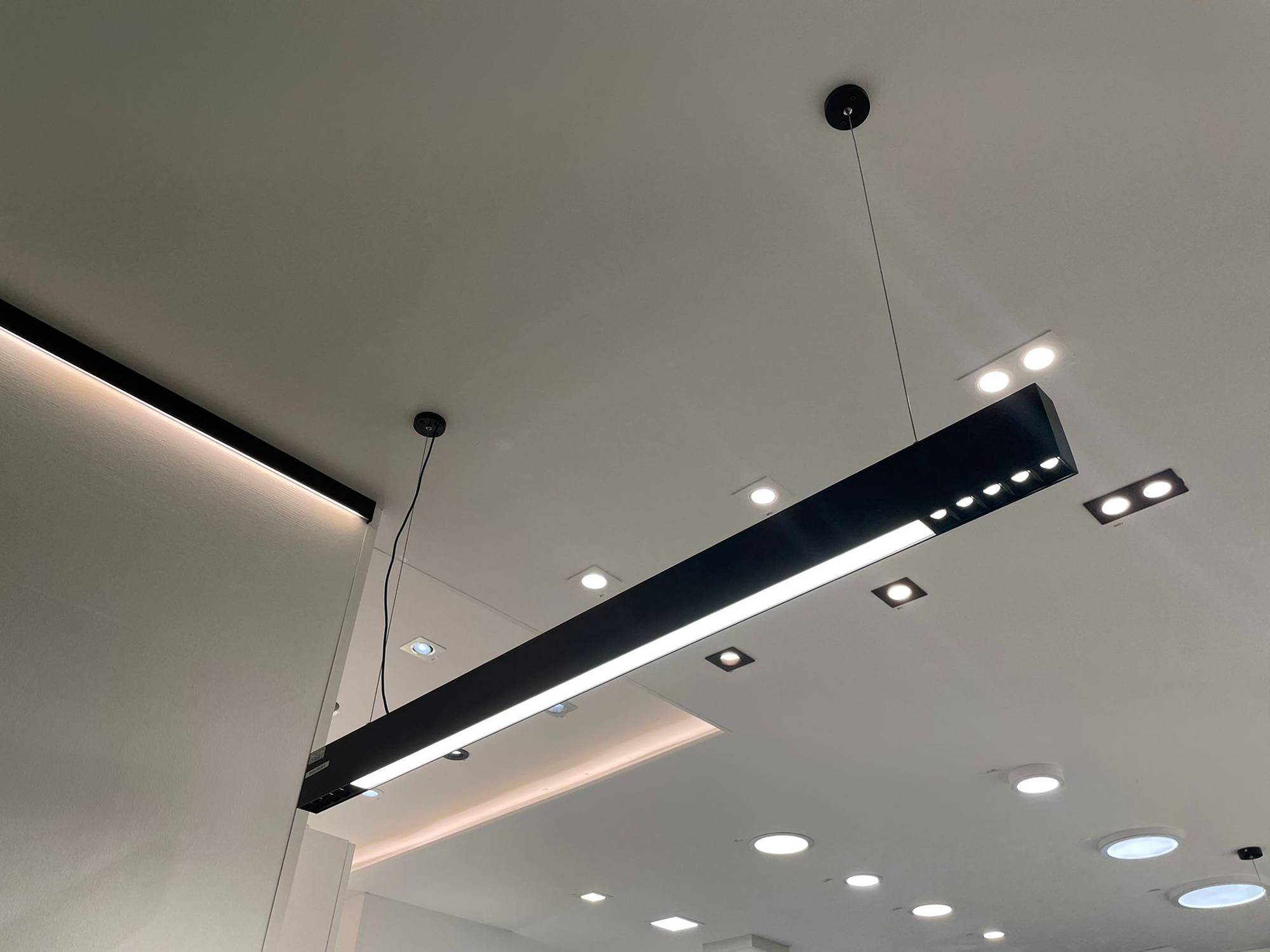 Svítidlo Ledstorella Line nad prodejním pultem. Led pásek na náhradním hliníkovém profilu ve stropě pro zajištění nepřímého světla a bodová a panelová světla na stropě. Ledstore.fi