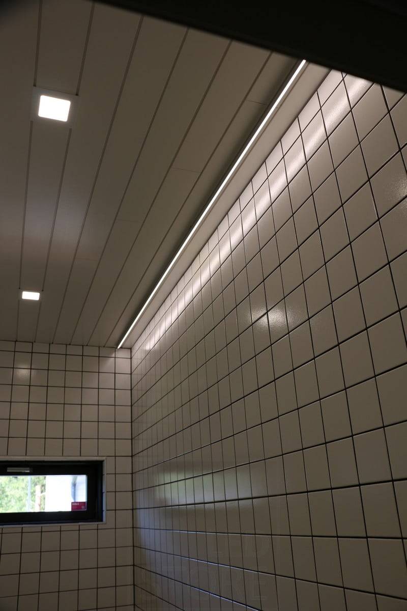Veletrh bydlení 2019: Led pásek na stropě vedle stěny, světlo se odráží od lesklé dlaždice. Ledstore.fi
