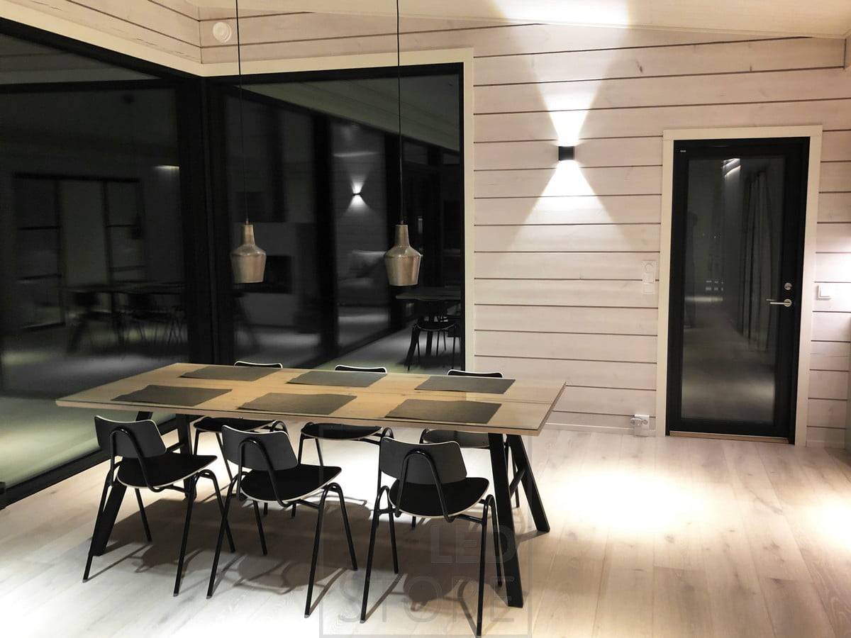 Černá nástěnná led lampa FUNK vytváří nepřímé náladové osvětlení na stěně v jídelním prostoru. Ledstore.fi