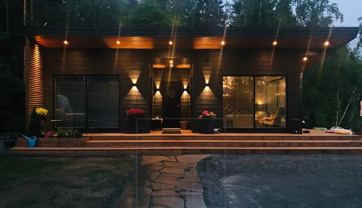 Černá nástěnná svítidla FUNK na stěně budovy, která osvětlují fasádu a vytvářejí venku atmosférické osvětlení. Nástěnná led světla FUNK mají nastavitelný úhel otevření podle vašich potřeb. Svítidlo je rovněž stmívatelné. Ledstore.fi
