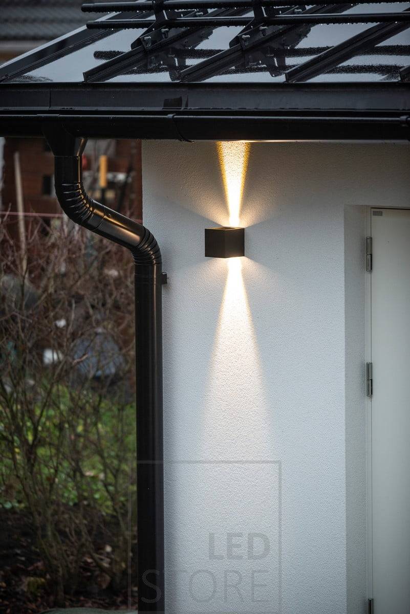 Černá obousměrná nástěnná svítidla FUNK led osvětlující fasádu garáže. Světlo směrem nahoru se zastavuje u okapu. Ledstore.fi