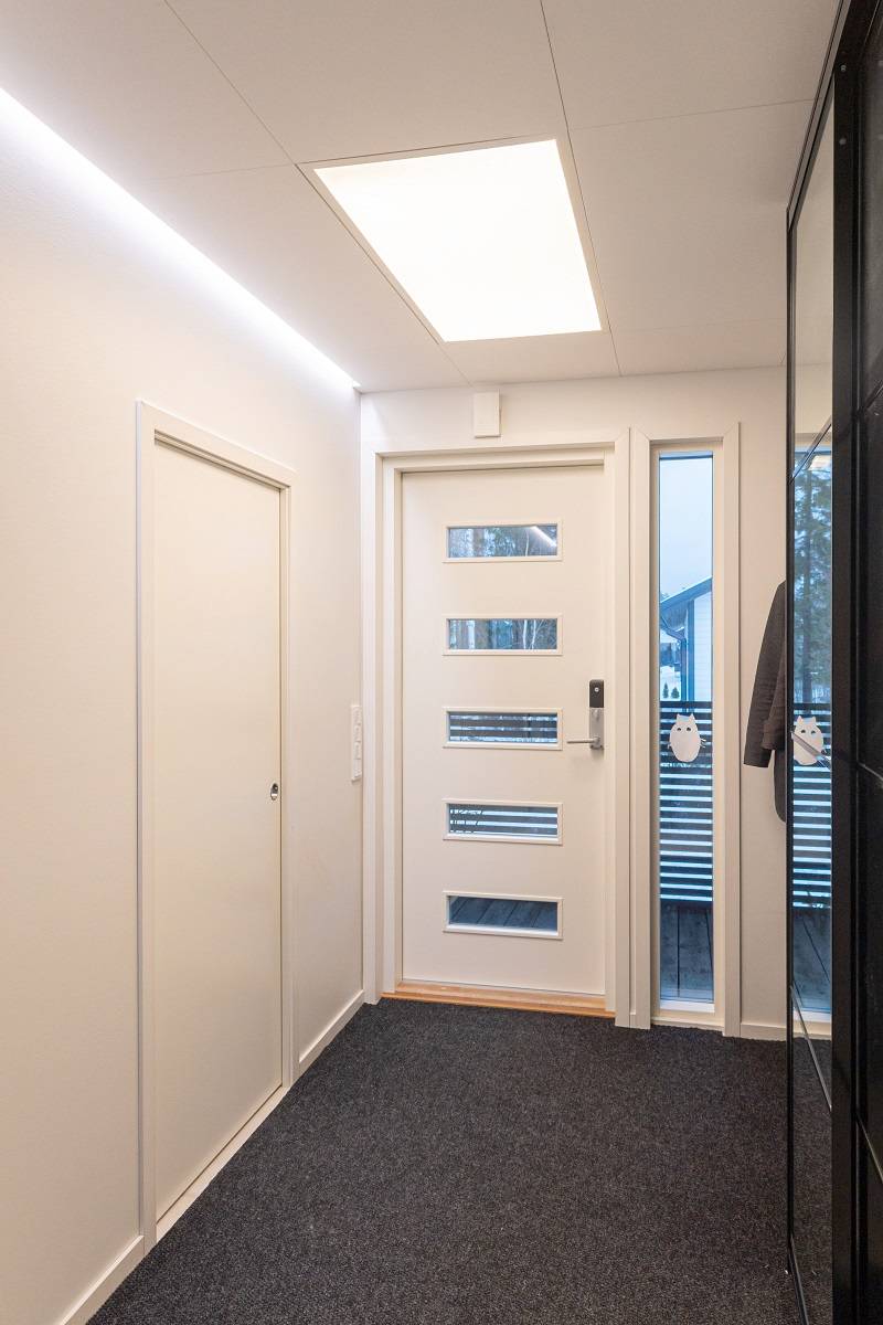 LED pásek ve výklenku mezi stěnou a stropem na jedné stěně a velké panelové svítidlo zapuštěné do stropu.