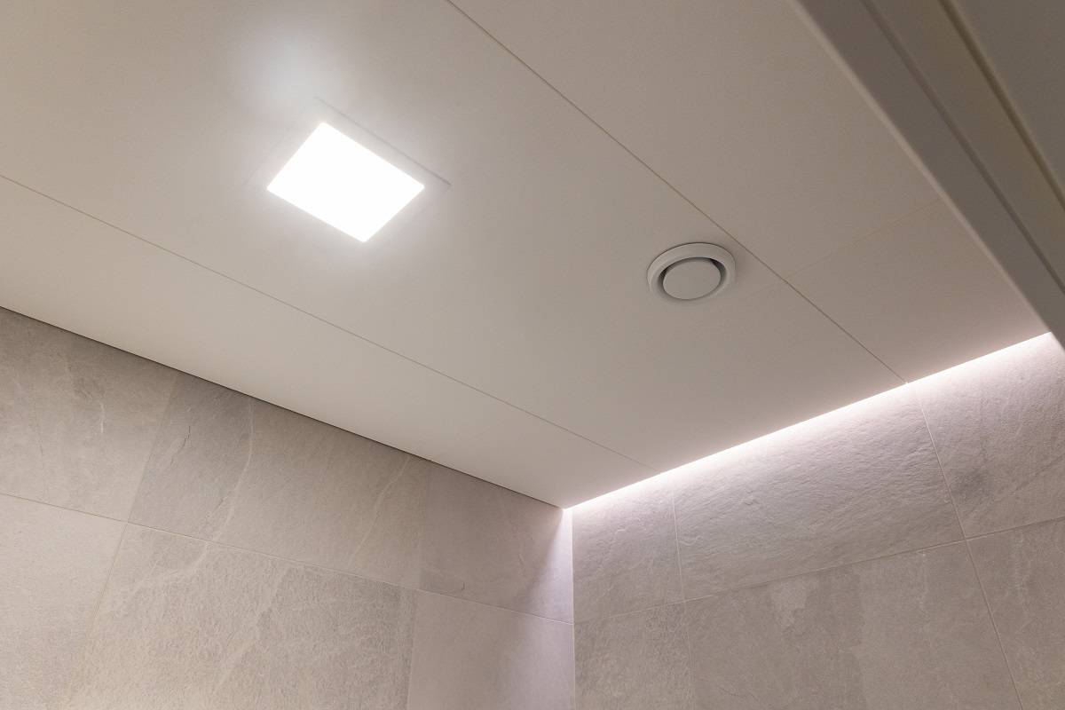 LED pásek ve výklenku mezi stropem a stěnou a malý zapuštěný čtvercový LED panel ve stropě.