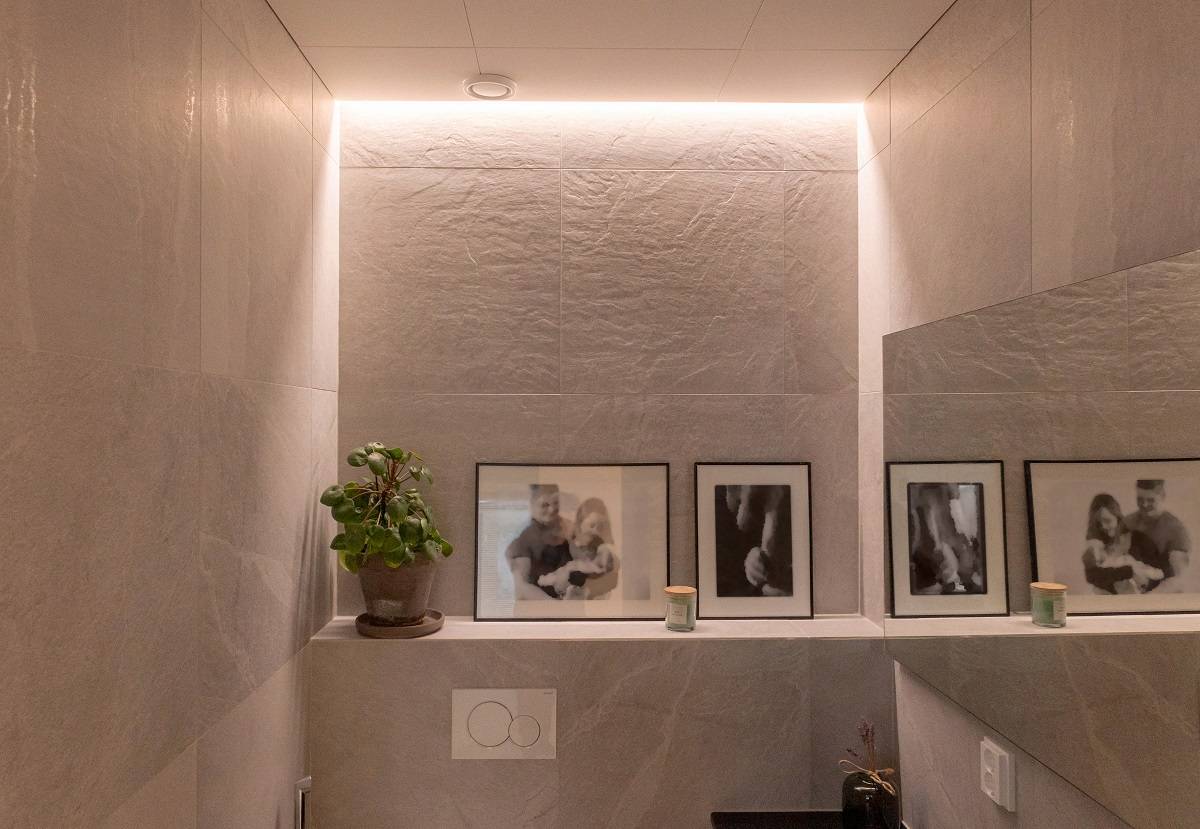 LED pásek namontovaný mezi stěnou a stropem v místnosti WC.