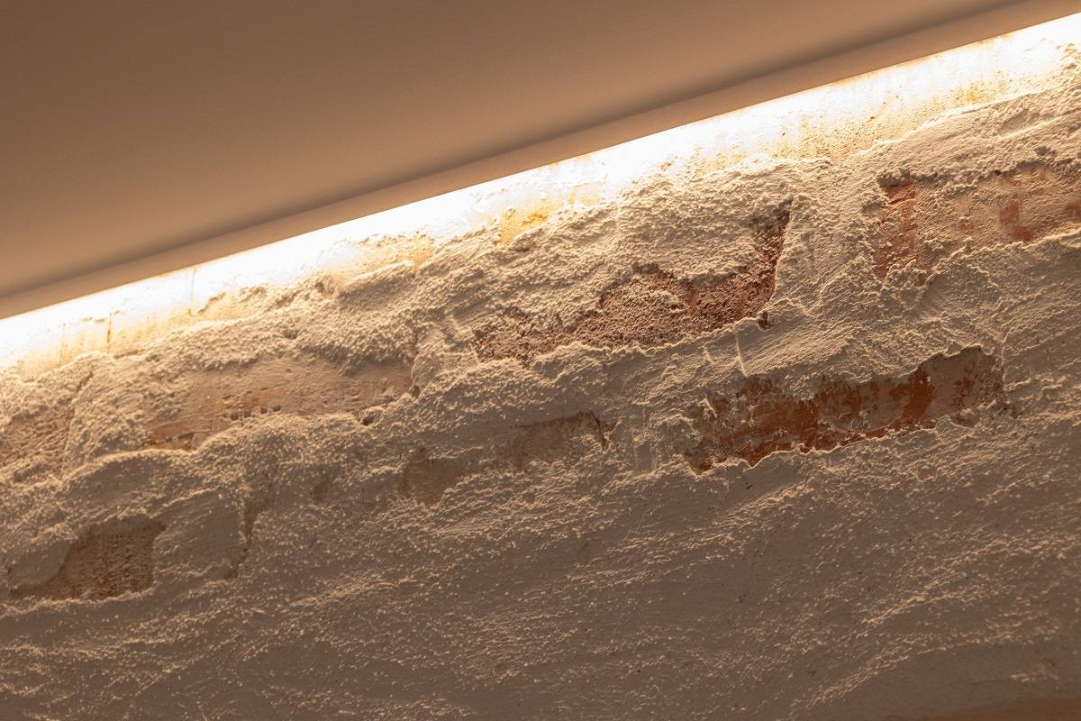 LED pás nainstalovaný na horním okraji akcentační stěny tak, aby svítil směrem dolů.