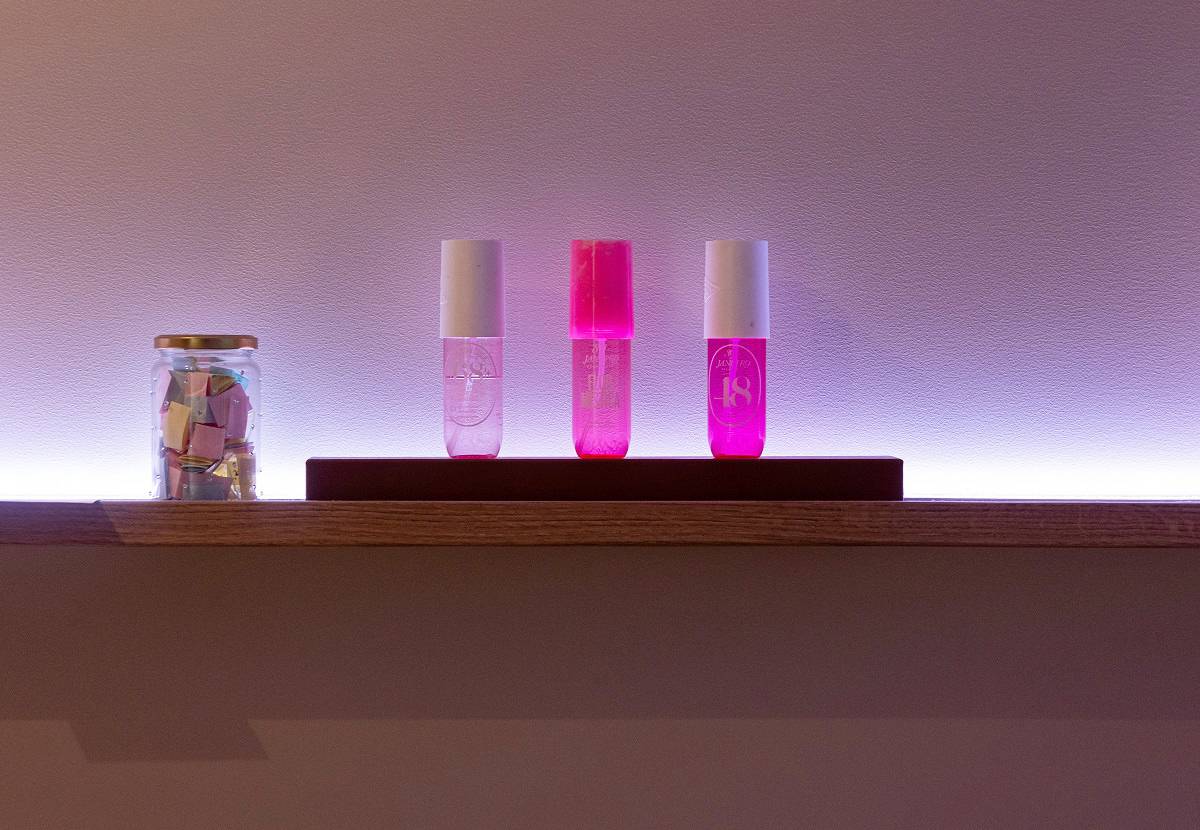 LED páska s nastavitelným odstínem, instalovaná za policí, vrhá na stěnu fialový světelný pruh.