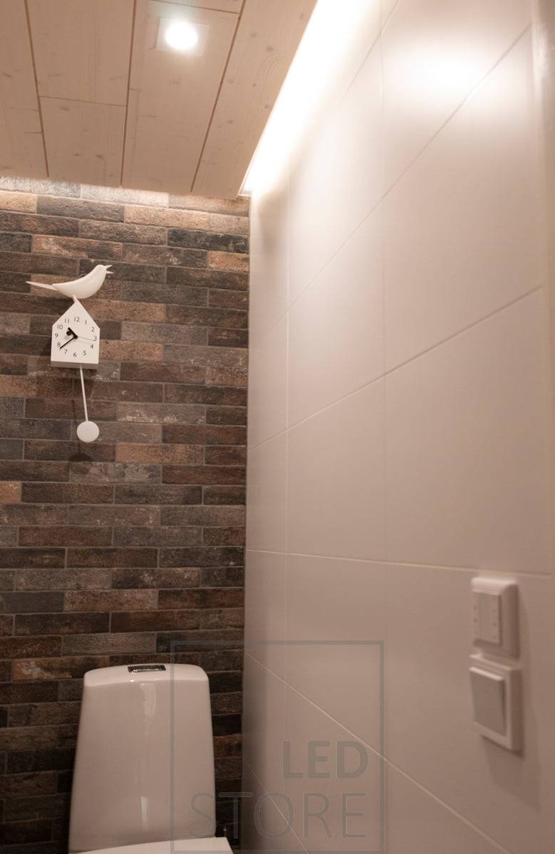 Bodové osvětlení s LED stropním svítidlem - LIGHT GREEN R023 a nepřímé osvětlení s bílým povrchovým profilem ve stropní drážce s páskem CCT 7,2 W/m. Bezdrátový ovladač namontovaný nad vypínačem světla je viditelný i na stěně.