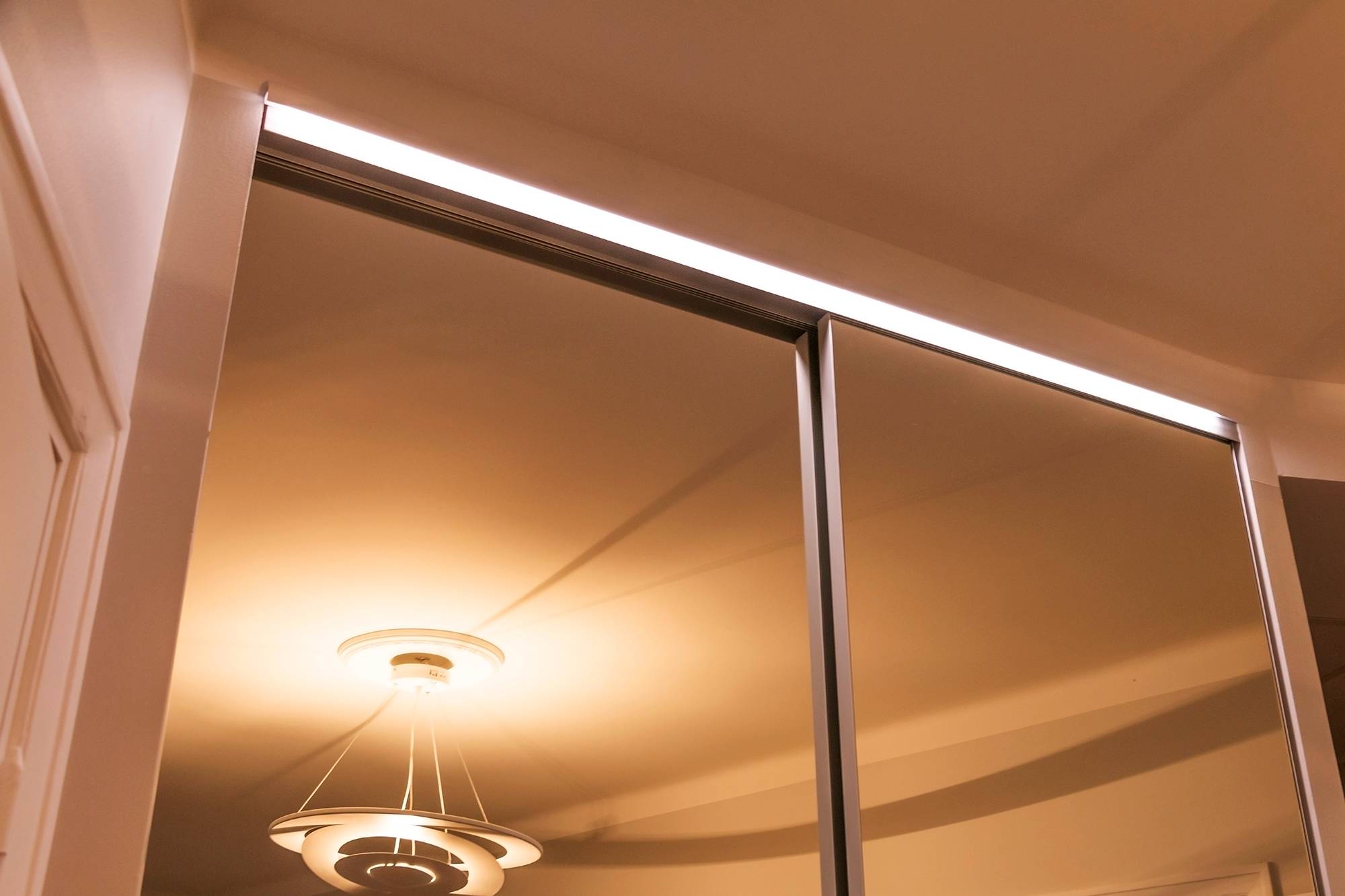 LED pásek na zásuvce šatní skříně, který osvětluje zrcadlo a vnitřek skříně nepřímým světlem. Ledstore.fi