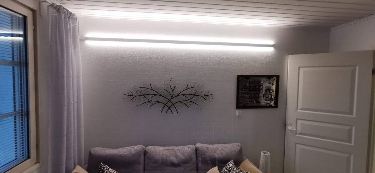 Za pohovkou, na stěně, obousměrný LED profil. Profil má dva LED pásky. Ledstore.fi