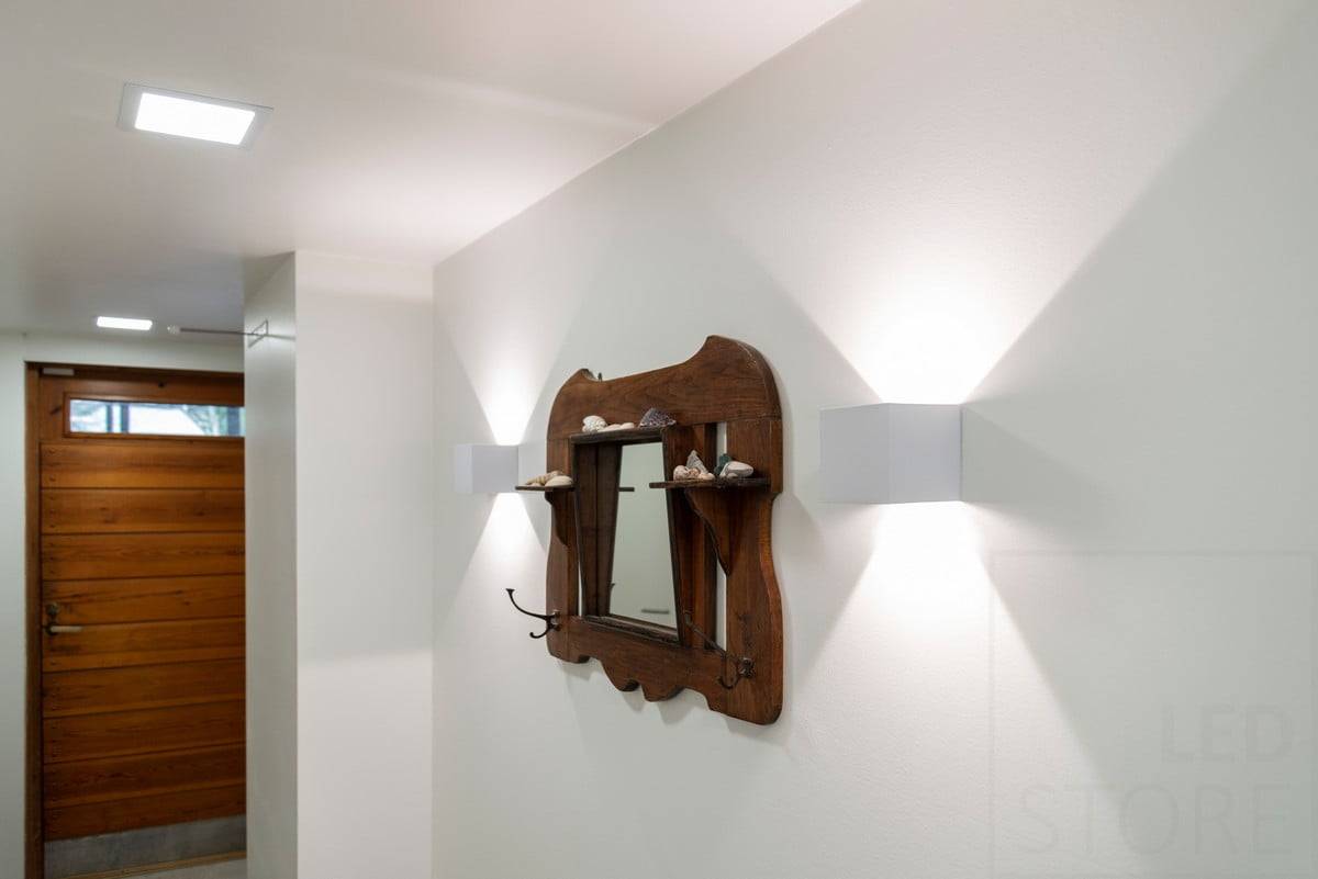Logo LED STORE: bílý text na zeleném pozadí s nápisem "LED" STORE nahoře. Bílý čtverec se nachází v obchodě s ekologickým osvětlením.