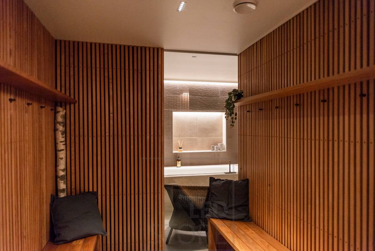 Šatna osvětlená 5 body LINJA. Lineární bodové svítidlo na stropě navazuje na designový tok říms na stropě. Ledstore.fi
