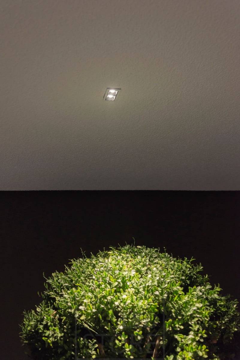 Malý reflektor LINJA 2 na střeše terasy, který vytváří atmosférické světlo a osvětluje venkovní rostliny. Ledstore.fi