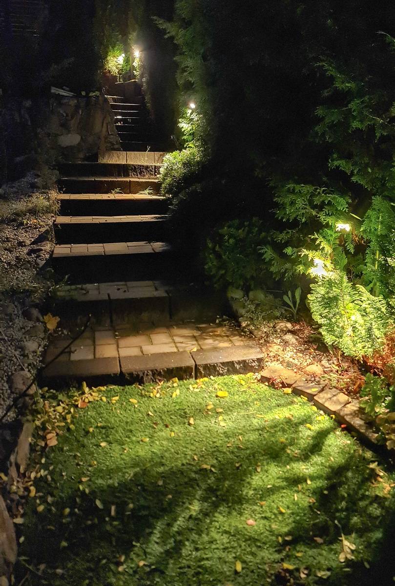 Svítidla Pillar TILT 2 instalovaná u schodiště. Svítidlo svítí a venku je soumrak.