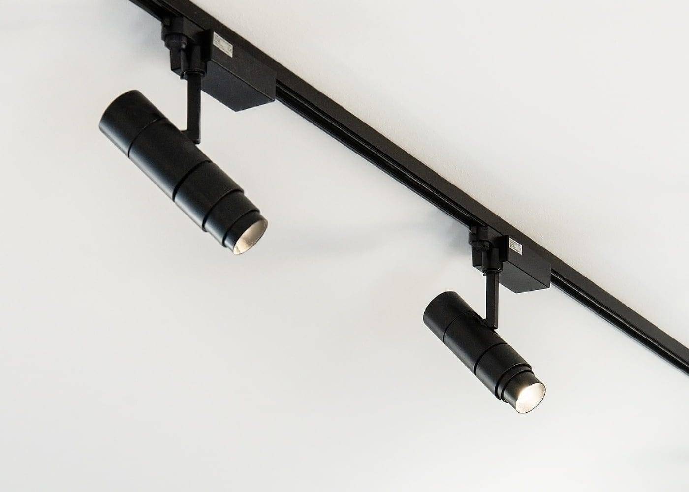Minimalistická konfigurace se dvěma černými válcovými světly LED na bílé střeše, upevněnými na černé liště, představuje moderní design osvětlení a nastavitelné úhly.