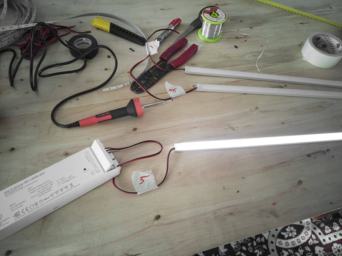 Pracovní stůl s elektrickým nářadím, LED pásky, dráty, svítícími zářivkami; včetně kleští, multimetru, pájecího drátu a napájecího zdroje.