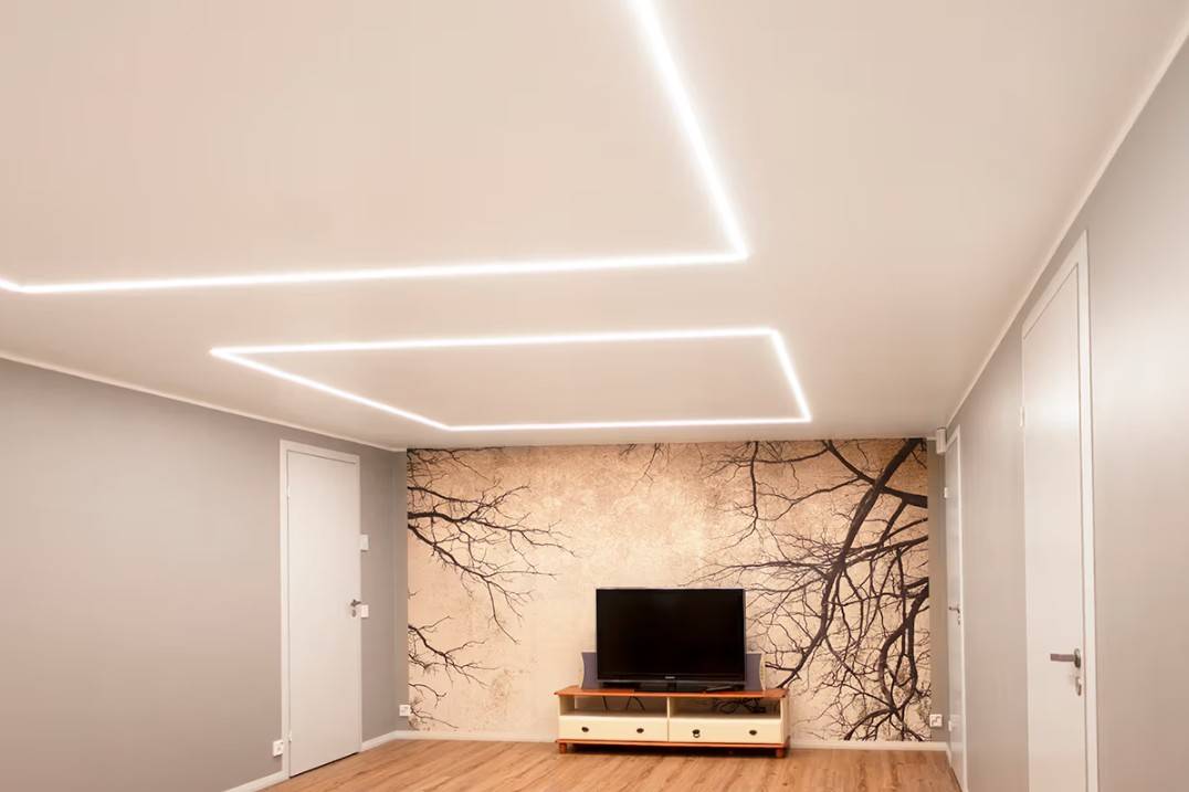 Minimalistický obývací pokoj v rodinném domě v Kaitamäki v Espoo, kde stropní LED svítidla od LedStore.fi vytvářejí stylové osvětlení. Obývací pokoj je vybaven televizním stolkem a výraznou nástěnnou malbou, kterou zvýrazňuje kvalitní LED osvětlení. 