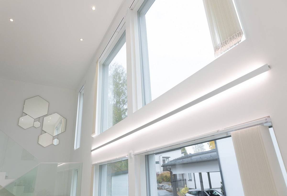 Interiérové osvětlení LedStore - atmosféra utvářená světlem Popis produktu v internetovém obchodě LedStore.fi: Moderní interiér se vyznačuje úžasnými velkými a vysokými okny, které jsou opatřeny stylovým LED osvětlením. Toto osvětlení umožňuje, aby dovnitř proudilo přirozené světlo. Na bílých stěnách je v blízkosti schodiště, které má skleněné zábradlí, umělecky uspořádána sada šestiúhelníkových zrcadel. Venku je příjezdová cesta lemována zaparkovanými automobily, které dotvářejí moderní styl.