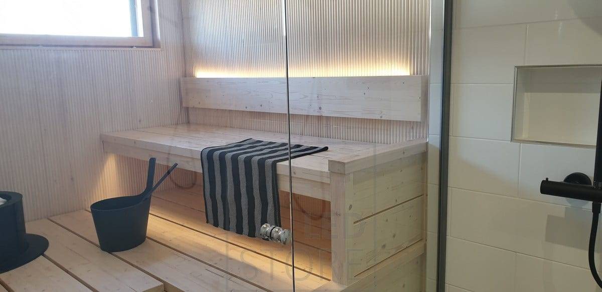 LED pásek na zadní straně opěradla sauny osvětluje náladové světlo směrem nahoru a dolů pod strop. Ledstore.fi