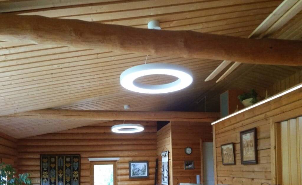 Na základě čeho se tvrdí, že světla LED jsou nebezpečná? Dřevěný interiér s kruhovými stropními LED svítidly osvětluje teplá záře; roubené stěny a strop vytvářejí rustikální kouzlo s zarámovaným uměním, hodinami a gobelíny.