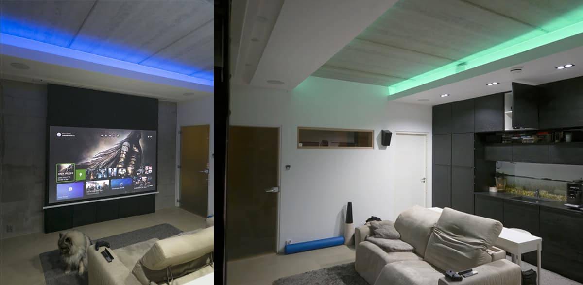 Moderní obývací pokoj s LED osvětlením LedStore.fi pro domácí kino, promítacím plátnem, pohodlnými sedačkami a psem na podlaze.